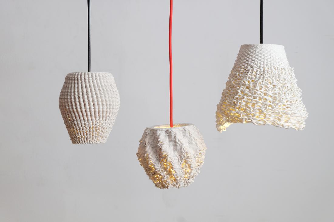 The lamps hang from thick black or red wires at different heights. They have textures similar to frayed textiles.