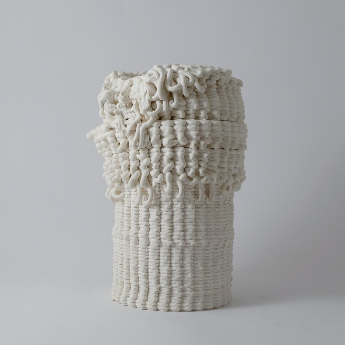The first piece, made of printed porcelain, in the shape of a tube. Its texture is heavy, resembling vertical lines when looked at from afar.