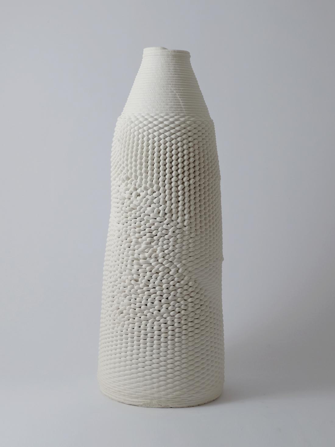 The second piece, also made of printed porcelain. It is shaped like a round beaker, with the top slightly thinner than the base, and a knitted-like texture.