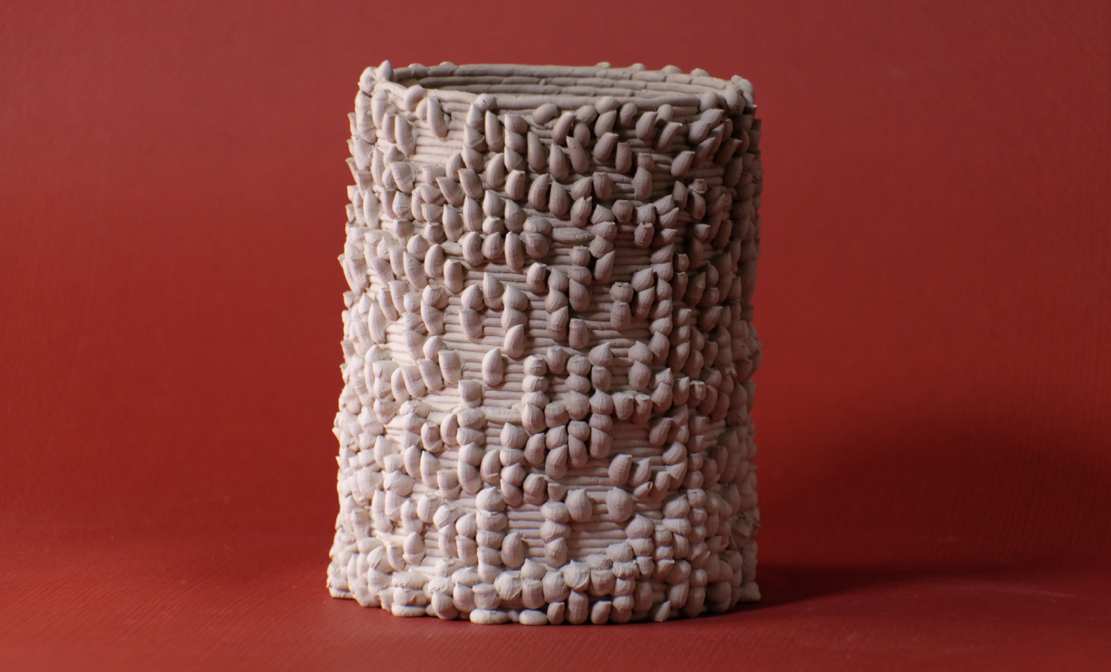 A porcelain cylindrical piece with a texture resembling small, numerous nubs coming out in random places.