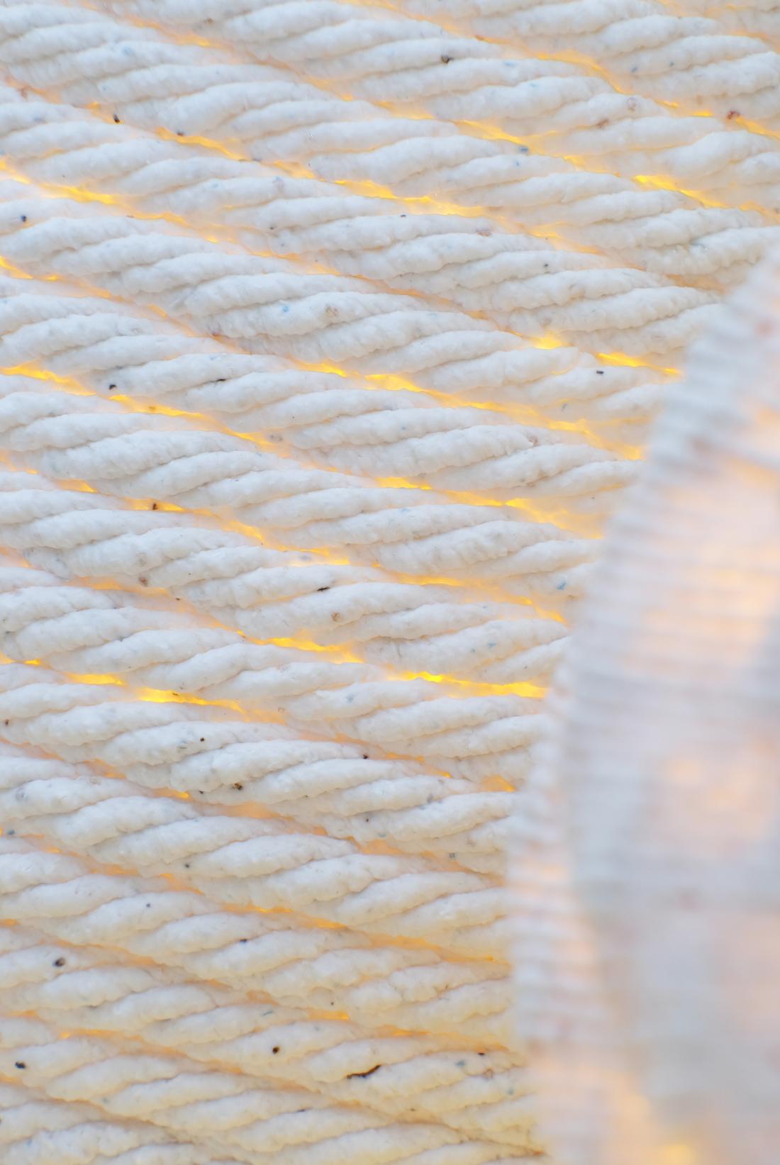 A close-up of the printed layer texture. The material is white porcelain, and small specks of colored glass-like material (from the recycled ceramic waste) are visible.