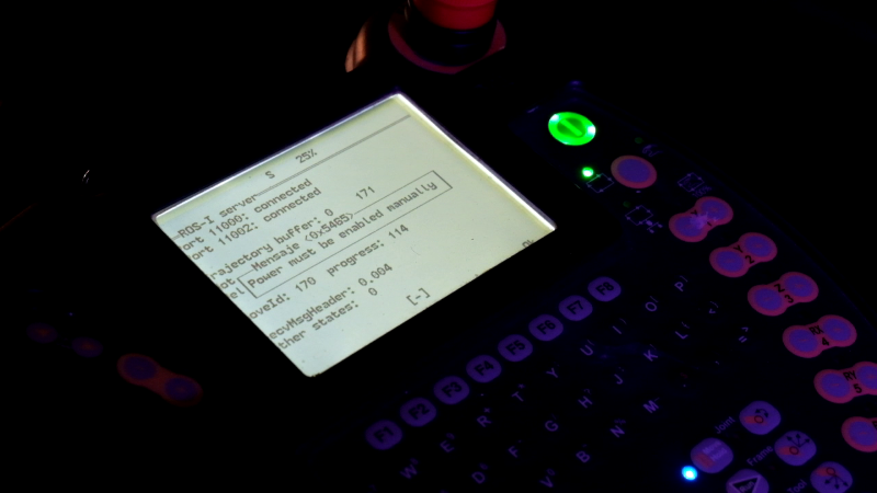The robot's controller in almost darkness, with glowing buttons. It has a screen showing technical information.